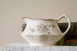 Homer Laughlin creamer showing its romantic floral pattern, graceful handle, and gilded spout.