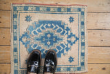 Short, distressed pile of Oushak rug, showing stepped blue medallion and ivory starbursts.
