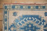 Oushak rug corner detail showing distressed texture, blue geometric designs, and ivory field.