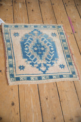 Distressed Oushak rug with sapphire blue medallion, stepped relief, and ivory ground.