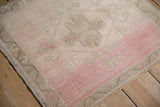Even wear to the knot heads on the low, distressed pile of a blush pink and sand Oushak rug.