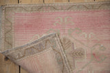 Hand-knotted construction and secured selvage on the back of a vintage pink Oushak rug mat.