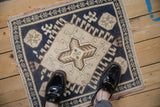 Distressed Oushak rug, quatrefoil medallion, hook-and-latch motifs, dusty navy blue and ivory.