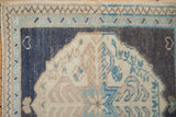 Corner of a vintage Oushak rug showing its intact side cord, geometric borders, and even wear.