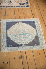 A small vintage Oushak mat in dusty navy and cream adding traditional pattern to a wood floor.