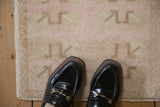 Even wear across the knot heads of a distressed Oushak mat in pink and cream.