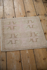 The low, even pile and distressed texture of a small vintage Turkish Oushak rug.