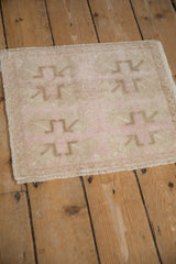 Vintage distressed Oushak mat from an angle, showing its even low pile in sand and dusty rose.