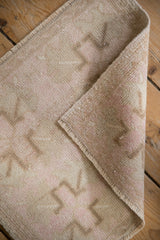 Evenly worn low pile and hand-knotted edge on a folded vintage Oushak rug mat.