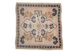 Distressed vintage Oushak square rug with faded pinkish-beige field, navy blue medallion, and floral bouquet.