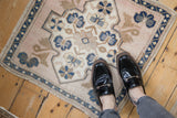 Corner of distressed vintage Oushak rug showcasing its worn fringe and floral border.