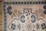 Vintage Oushak corner detail with dusty pink field, navy finned floral motif, and even distressed pile.