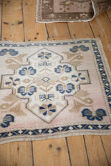 Distressed Oushak rug detail showing dusty blue, ivory floral motifs, meandering border, and even pile.