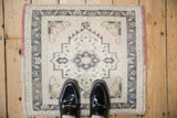 Vintage Oushak mat shown to scale, featuring a distressed geometric medallion in ivory and blue.