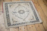 Angled view of a distressed Oushak square rug with a geometric stepped medallion in muted tones.
