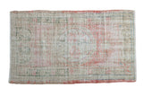 Vintage distressed Oushak rug with a faded geometric medallion in soft pink, ivory, and sage green.