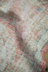 Detailed view of the distressed, hand-knotted pile in dusty blush and sage green.
