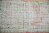 Close-up of the distressed rug's low pile showing wear to the foundation and knot heads.