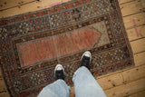 Distressed brick red field with intricate floral and geometric borders on vintage Melas rug.
