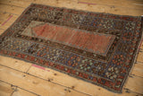 Textured Melas rug close-up showing distressed pile, faded field, and intricate floral border motifs.