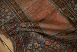 Distressed vintage Melas rug showcasing even pile wear, brick red, royal blue, and brown geometric patterns.