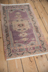 Distressed aubergine pile with meandering vine border in antique ivory, seafoam, and pale terra cotta.