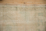 Distressed Oushak rug's worn pile texture featuring cream, pale green, and faded pink hues.