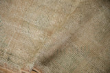 Close-up of distressed vintage Oushak rug pile, showing wear and faded cream, sage tones.