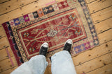 Distressed vintage Oushak rug, featuring abrash, geometric florals, in black cherry red, violet, and ivory.