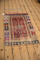 Distressed Oushak rug border showing geometric violet, red, and ivory abrashed florals.