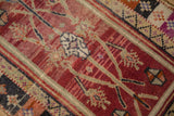 Distressed vintage Oushak rug texture, showing geometric bouquet motifs in black cherry red and ivory.