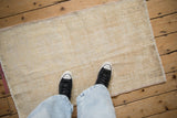 Distressed Oushak rug texture in cream and beige tones, with worn foundation visible underfoot.