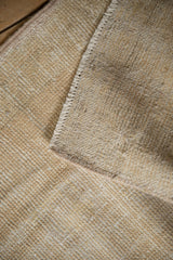 Vintage distressed Oushak rug with visible foundation and soft beige worn pile.