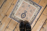 Overhead view of a small vintage Oushak rug mat showing its decorative scale on a wood floor.
