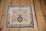 Angled view of a distressed square Oushak rug with a potted plant motif on a peach field.