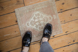 Distressed vintage Oushak rug corner, pale rose with ivory stepped medallion and floral border.