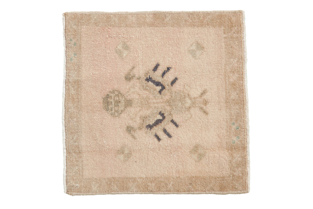 Distressed vintage Oushak square mat with a central floral design in sand, dusty rose, and soft navy.
