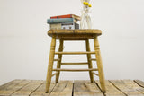 Antique primitive stool with distressed yellow-green paint and weathered wood.