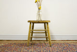 Weathered wooden legs and rungs of the rustic stool with chippy yellow-green paint.