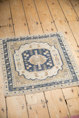 Distressed vintage Oushak rug corner, dusty navy interconnected vine border, with even pile wear.