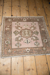 Distressed Oushak rug corner, dusty blush pinwheel florals, pale coffee brown border, low pile.