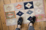 Distressed Oushak rug, worn texture underfoot, showing ivory, navy, tangerine geometric panels.
