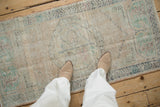 Distressed vintage Oushak runner showcasing low pile, visible foundation, and muted floral details.