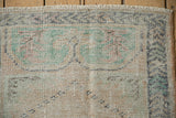 Textured view of vintage Oushak runner's distressed pile, revealing foundation and faded colors.