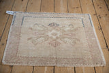 Corner detail of a distressed vintage Oushak rug showing worn sandy beige pile and navy border line.