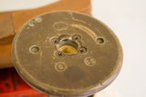 Detail of a vintage industrial spool's top, showing bronze patina, exposed screws, and numerals.