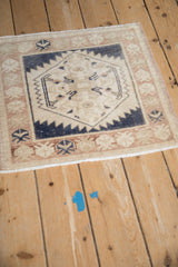 Corner detail of a vintage Oushak mat with a pomegranate motif border and evenly worn pile.