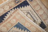Folded corner of a distressed Oushak rug, showing the low hand-knotted pile and secured edging.