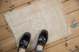 Distressed vintage Oushak square mat, faded ivory, pale pink tones, and worn pile.