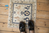 Distressed Oushak rug's ivory field with navy and beige bird-like floral arabesques.